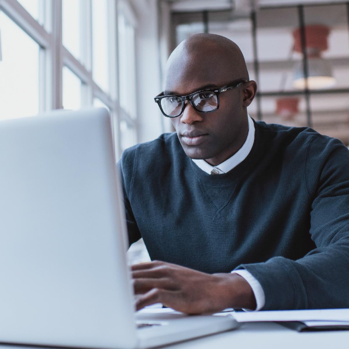 A businessman using a laptop in an office setting.