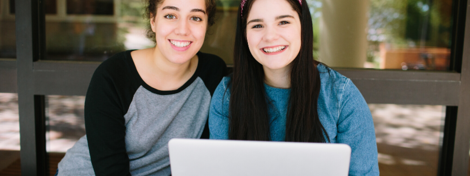 Two college students using a computer outdoors on the campus of Columbia International University